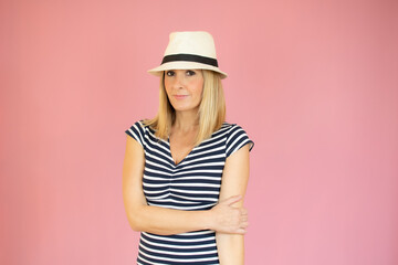 Beautiful woman with straw hat smiling over pink background.