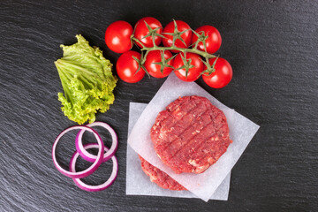 The raw ingredients for the homemade burger on black slate background. Top view.