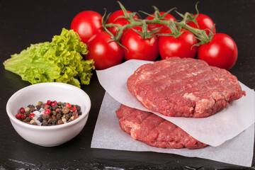 The raw ingredients for the homemade burger on black slate background.