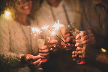 group of four people having fun and enjoying holding glasses of champagne and sparklers celebrating the happy new year together
