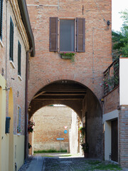 Fototapeta na wymiar Ferrara, Italy. Cobbled street in the old town with archway.