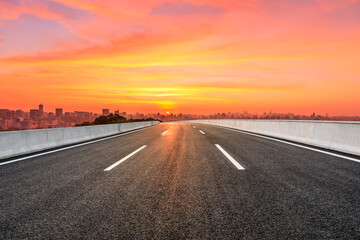 Empty asphalt road and city skyline with buildings in Hangzhou at sunrise.
