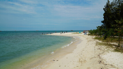 View of the beach and blue sky, white sand and tourists.