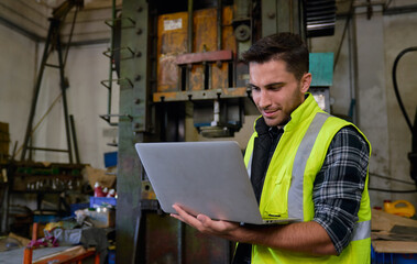 Smart caucasian engineer smile when looking to laptop in manufacturer industrial
