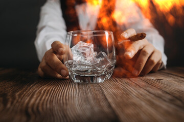 Close-up of two glasses one empty one with ice on bar counter with two male bartenders on background