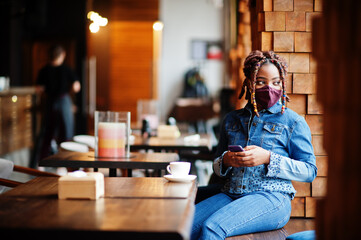 Stylish african american woman with dreadlocks afro hair, wear jeans jacket and face protect  mask...
