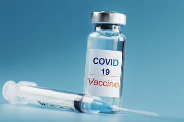 Syringe and ampoule with a vaccine against the Covid-19 virus against diseases on a blue background.