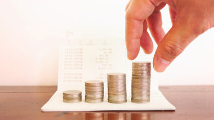 Hand picked up the coins stack which lay on book bank, finance and business concept.