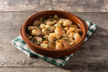 Garlic prawns in crockpot on wooden table