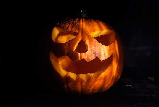 Carved Halloween pumpkin, jack lantern (Jack-o'-lantern). Spooky laughing, scary head in the darkness.