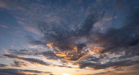 Sunset sky with clouds in blue and orange colors.