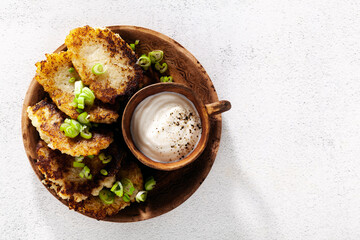 potato pancakes with yogurt and green onions and black pepper. in clay pots on a white background