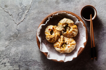 Baozi buns with vegetables and mushrooms in a wooden basket on a concrete table