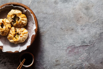 Baozi buns with vegetables and mushrooms in a wooden basket on a concrete table