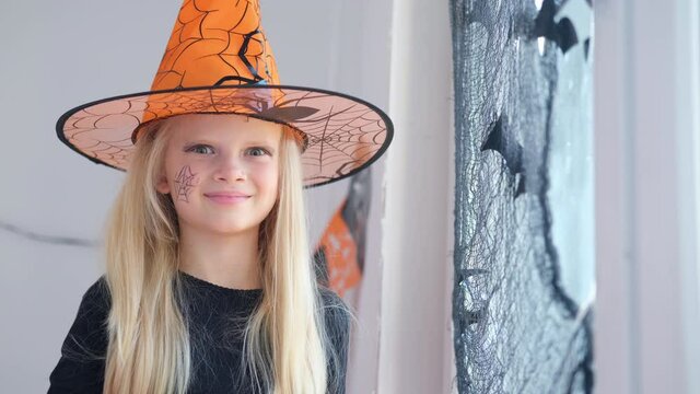 4k. Laughing happy blonde girl in witch costume preparing for Halloween at home.