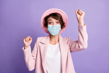 Photo of lucky girl use medical safety mask dressed pink retro blazer open mouth raise fists isolated purple color background