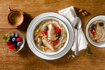 quinoa porridge with caramelized pear and berries on a wooden table. morning breakfast with coffee