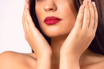  Brunette girl. Beautiful model with red lips. Hands partially covering her face. Beauty and Makeup concept