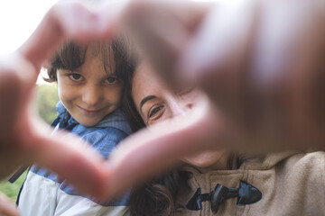 Boy with mom folded fingers in the shape of a heart.