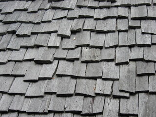 Weathered wooden roof composed of overlapping wooden boards. Rough and uniform texture.