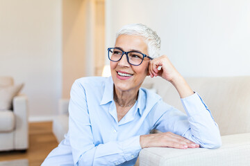 Senior woman looking at camera. Successful mature business woman wearing eyeglasses. Happy old professor in standing in college library with gray hair.