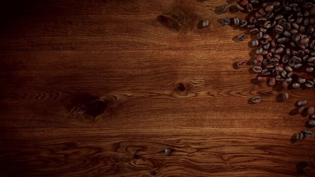 Super slow motion shot of coffee beans falling onto an oak wooden surface.