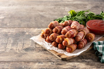 Pig in blankets. Sausages wrapped in smoked bacon on wooden table.Copy space	