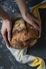 A loaf of bread, homemade. Yellow towel, grey background.