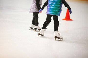 Figure skates on ice. Figure skating school. Young figure skaters practicing at indoor skating rink. Kid learning to ice skate.