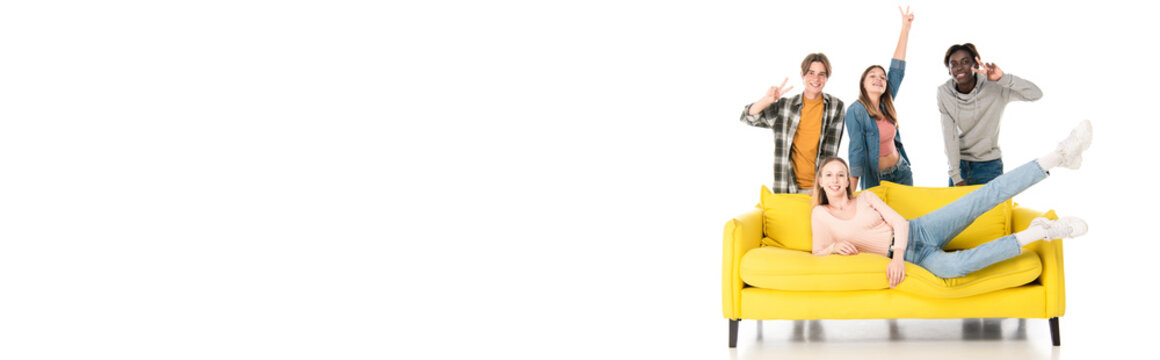 Panoramic Shot Of Cheerful Multiethnic Teenagers Showing Peace Sign Near Yellow Couch On White Background