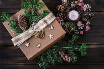 Gift box, spruce twigs, cones, candlestick on wooden background