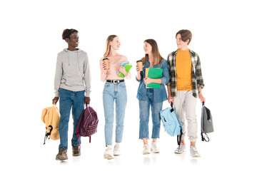 Smiling multicultural teenagers with coffee to go, books and backpacks walking on white background