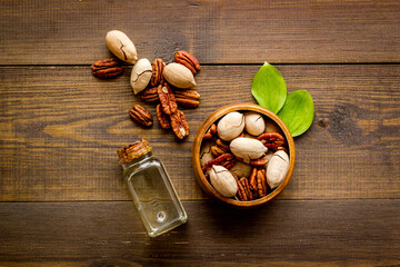 Pecan essential oil with raw nuts, top view