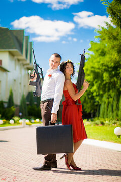 A guy with a girl in evening dresses with a gun and a suitcase of money