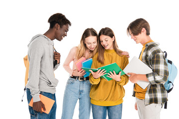 Positive multicultural teenagers with books and laptop looking at copy book isolated on white