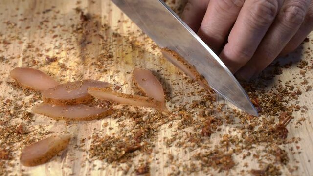 person cuts the dried meat of the chicken fillet with spices