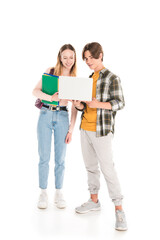 Teen boy holding laptop near friend with notebooks on white background