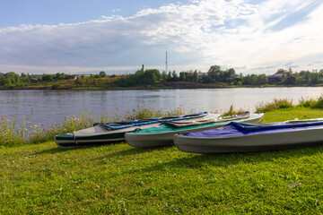 Fototapeta na wymiar colorful boats for sports and canoe trips on the ground near a natural reservoir,river,lake