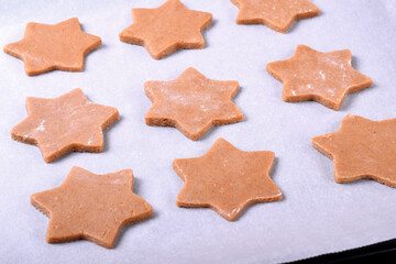 Star shaped dough for gingerbread shortbread cookies on the pastry parchment ready to be baked 