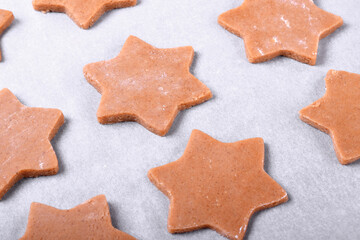 Star shaped dough for gingerbread shortbread cookies on the pastry parchment ready to be baked 