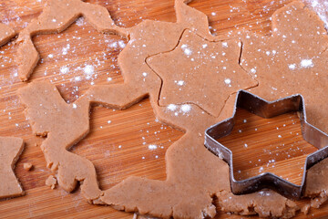 Shortbread dough for gingerbread cookies rolled on the wooden board. Cutting out star shaped cookies