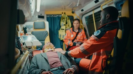Female and Male EMS Paramedics Ride to Healthcare Hospital with an Injured Patient on the Ambulance. Black African American Emergency Care Assistant Checking Up on the Sick Young Man with Neck Collar.