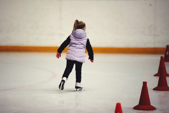 Figure skating school. Young figure skater practicing at indoor skating rink. Kid learning to ice skate.