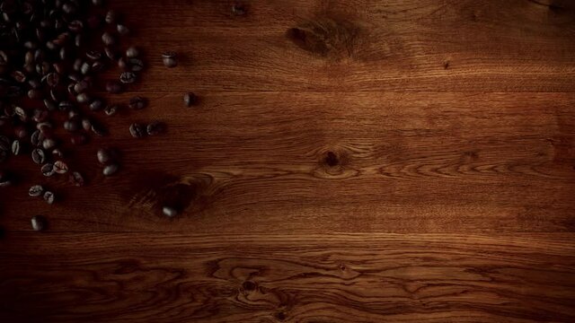 Super slow motion shot of coffee beans falling onto an oak wooden surface.