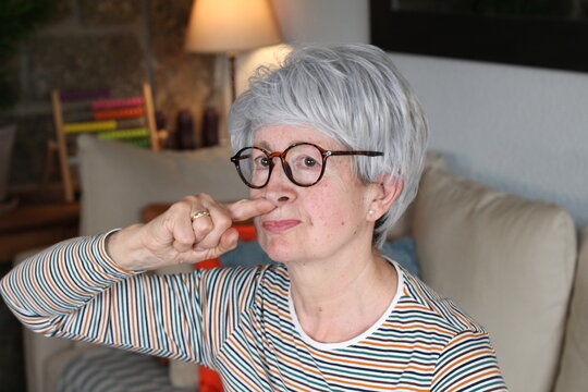 Senior woman picking her nose at home 