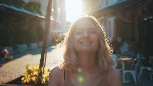 Portrait of nice beautiful blonde woman smiling at camera showing braces on teeth. Playful caucasian girl flirting with happy smile. Sunsets. Outdoors.