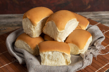 
small homemade milk breads in basket with rustic gray cloth on wooden table