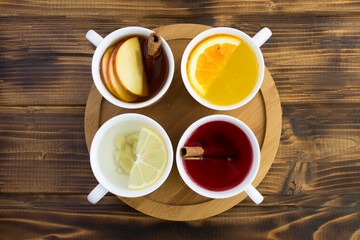 Top view of different teas in the white cups on the round wooden cutting board