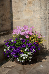 UK. 2020.  A flower display in a tub close to and old wall