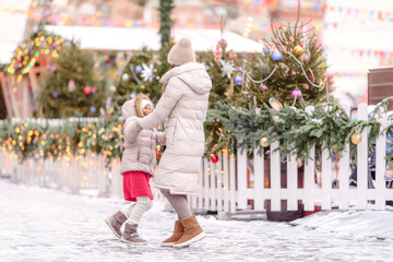 Cheerful family, mother and little girl having fun on Christmas market.